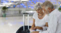 Aspire Blog - Travelling with Medicare - Older couple sitting at the airport looking at a passport