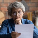 Aspire Blog - Questions about Medicare - Woman with glasses starting at a paper thinking