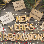 New Year's resolutions such as save money and be happy written on cards