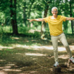 Older woman balances on log; balance can help prevent falls